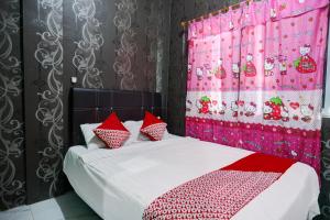 une chambre avec un lit avec des oreillers rouges et blancs dans l'établissement Hotel O Penginapan Pelangi, à Batam Center