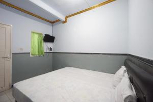 OYO 93628 Scorpion Guest House & Beach في تولونغاغونغْ: غرفة نوم صغيرة بها سرير وتلفزيون