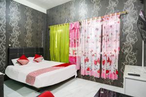 - une chambre dotée d'un lit avec des rideaux roses et verts dans l'établissement Hotel O Penginapan Pelangi, à Batam Center