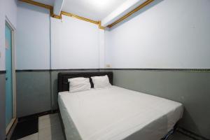 OYO 93628 Scorpion Guest House & Beach في تولونغاغونغْ: غرفة نوم صغيرة بسرير ابيض مع وسادتين