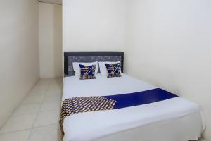 - un lit avec des oreillers bleus et blancs dans l'établissement SPOT ON 93724 Songgong Homestay, à Kuta Lombok