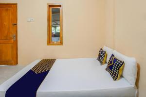 - un lit blanc avec des oreillers bleus et jaunes dans l'établissement SPOT ON 93724 Songgong Homestay, à Kuta Lombok