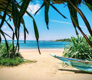 a blue boat sitting on a beach next to the ocean at Milk House Mirissa, Entire Home, Authentic Village in Mirissa