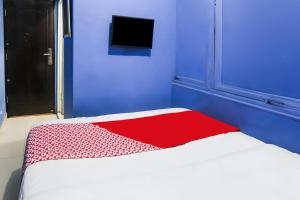 a blue room with a bed with a red blanket at Hotel O Iconiq Rooms in Bekasi