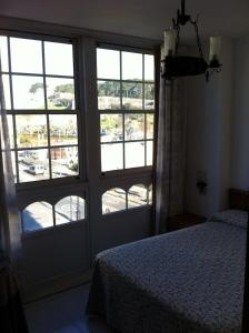 1 dormitorio con 1 cama y puerta con ventanas en Hotel Pinzon, en Baiona