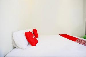 un letto bianco con due cuscini rossi sopra di Hotel O Sejolie Sibayak a Berastagi Altre 20 foto
