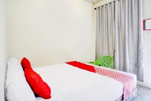 una camera da letto con un letto con cuscini rossi e bianchi di Hotel O Sejolie Sibayak a Berastagi