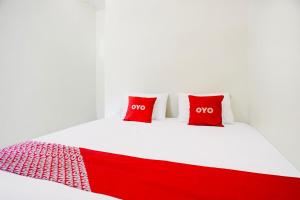 un letto rosso e bianco con due cuscini rossi sopra di Hotel O Sejolie Sibayak a Berastagi