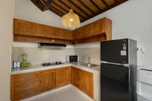 a kitchen with wooden cabinets and a black refrigerator at Belvilla Prakriti Near Monkey ForestNearCampuhan Ridge Walk in Ubud