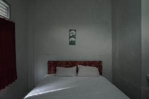 a bed with two pillows and a picture on the wall at Hotel O Pondok Bintang in Kendari