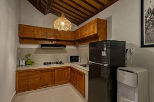 a kitchen with wooden cabinets and a black refrigerator at Belvilla Prakriti Near Monkey ForestNearCampuhan Ridge Walk in Ubud