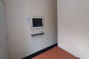a room with a small tv on a white wall at Hotel O 45 Guest House in Sragen +16 photos