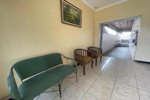 a waiting room with a green couch and chairs at Hotel O 45 Guest House in Sragen