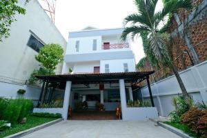 a white building with a porch and a palm tree at Mowin Boutique Hotel & Residence in Phnom Penh