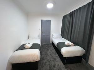 阿克斯桥OYO Greenway Stays的配有衬衫的小客房内的两张床