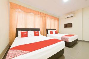 a bedroom with two beds with red and white pillows at Hotel O Gest Inn in Kota Tinggi