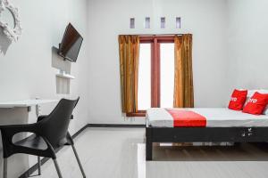 a bedroom with a bed and a window and a chair at Hotel O Regina Homestay Syariah in Surabaya