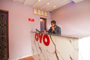 a man sitting at a counter looking at his cell phone at OYO 817 Hotel Garden Flower in Kathmandu +97 photos