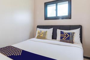 a bedroom with a bed with pillows and a window at Hotel O 3n Homestay Syariah in Sidoarjo