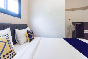 a bedroom with a white bed with pillows and a fan at Hotel O 3n Homestay Syariah in Sidoarjo