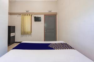 a bedroom with a white bed with a blue blanket on it at Hotel O 3n Homestay Syariah in Sidoarjo +18 photos