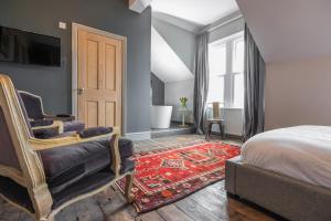 a bedroom with a bed and a chair and a television at St Valery Boutique Bed + Breakfast in Alnmouth