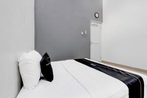 a bedroom with a white bed with a black pillow at Capital O 93939 Oikodomeo Syariah in Salatiga