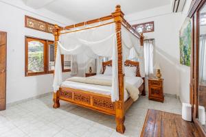 a bedroom with a four poster canopy bed at Belvilla Ratna Resort Ubud PalaceNearUbud Palace in Ubud