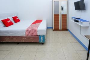 una camera da letto con un letto con cuscini rossi e una TV di OYO 93995 Griya Va Syariah a Serang