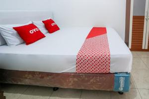 un letto con cuscini rossi e bianchi di OYO 93995 Griya Va Syariah a Serang