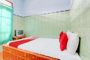 a bedroom with a bed with red and white pillows at Hotel O Homestay Baronsari in Kemadang +26 photos