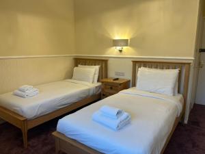 two beds in a room with towels on them at Rothwell House Hotel in Kettering