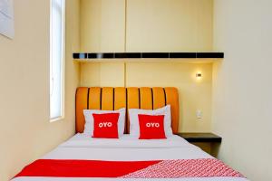 two red pillows on a bed in a room at Hotel O Helvetia Near Plaza Millenium Formerly Sunny Inn in Pulauberayan