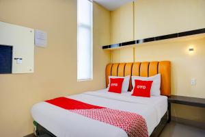 a bedroom with a bed with two red pillows at Hotel O Helvetia Near Plaza Millenium Formerly Sunny Inn in Pulauberayan +24 photos