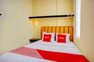 a bedroom with a bed with two red pillows at Hotel O Helvetia Near Plaza Millenium Formerly Sunny Inn in Pulauberayan