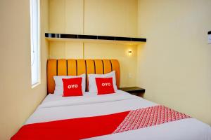 two red pillows on a bed in a room at Hotel O Helvetia Near Plaza Millenium Formerly Sunny Inn in Pulauberayan