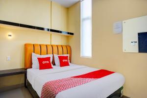 a bedroom with a bed with two red pillows at Hotel O Helvetia Near Plaza Millenium Formerly Sunny Inn in Pulauberayan