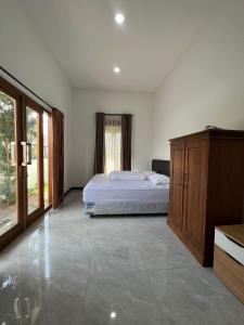 a bedroom with a bed and a wooden cabinet at Villa Dua Kota - Dekat Malang dan Batu - 10 menit - MURAH RAME-RAME in Dau