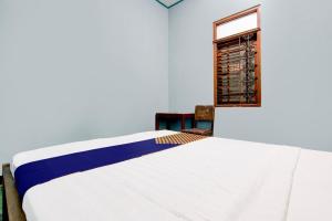a bedroom with a white bed and a window at Hotel O Agung in Purwokerto