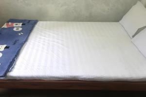 a bed with a white sheet on top of it at Hotel O Homestay Banyumili Samigaluh in Semigaluh
