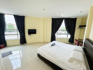 a bedroom with a bed and a tv and windows at Hotel O Furich Hotel in Mentekab