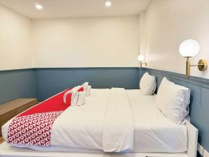 a bedroom with a large white bed with red and white pillows at Collection O The Singha Chiangmai Hotel in Chiang Mai