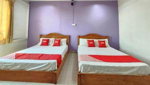 two beds in a room with purple walls and red pillows at Hotel O Ban Cheong in Kangar +26 photos