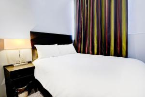 a bedroom with a large bed and a curtain at London Shelton Hotel, Finsbury Park in London