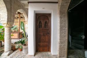 a wooden door in a house with a brick wall at Hotel Boutique Patio del Posadero in Córdoba