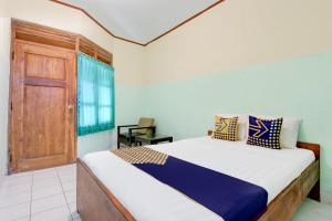 - une chambre avec un lit et une porte en bois dans l'établissement Hotel O Pondok Wisata Kaliandra Kaliurang, à Yogyakarta
