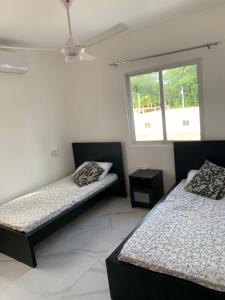 two beds in a room with a window at Villa Muñoz in San Felipe de Puerto Plata +2 photos
