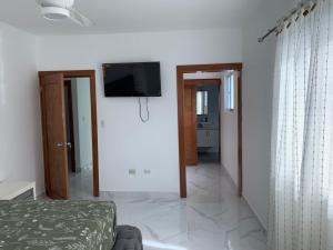 a white room with a tv on the wall at Villa Muñoz in San Felipe de Puerto Plata