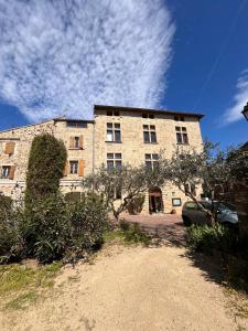 a large brick building with a car parked in front of it at auberge des trois ami-es in Vinezac