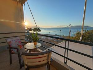 Un balcón con mesa y sillas y vista al mar. en Νηρηίδες so blue, en Arkitsa